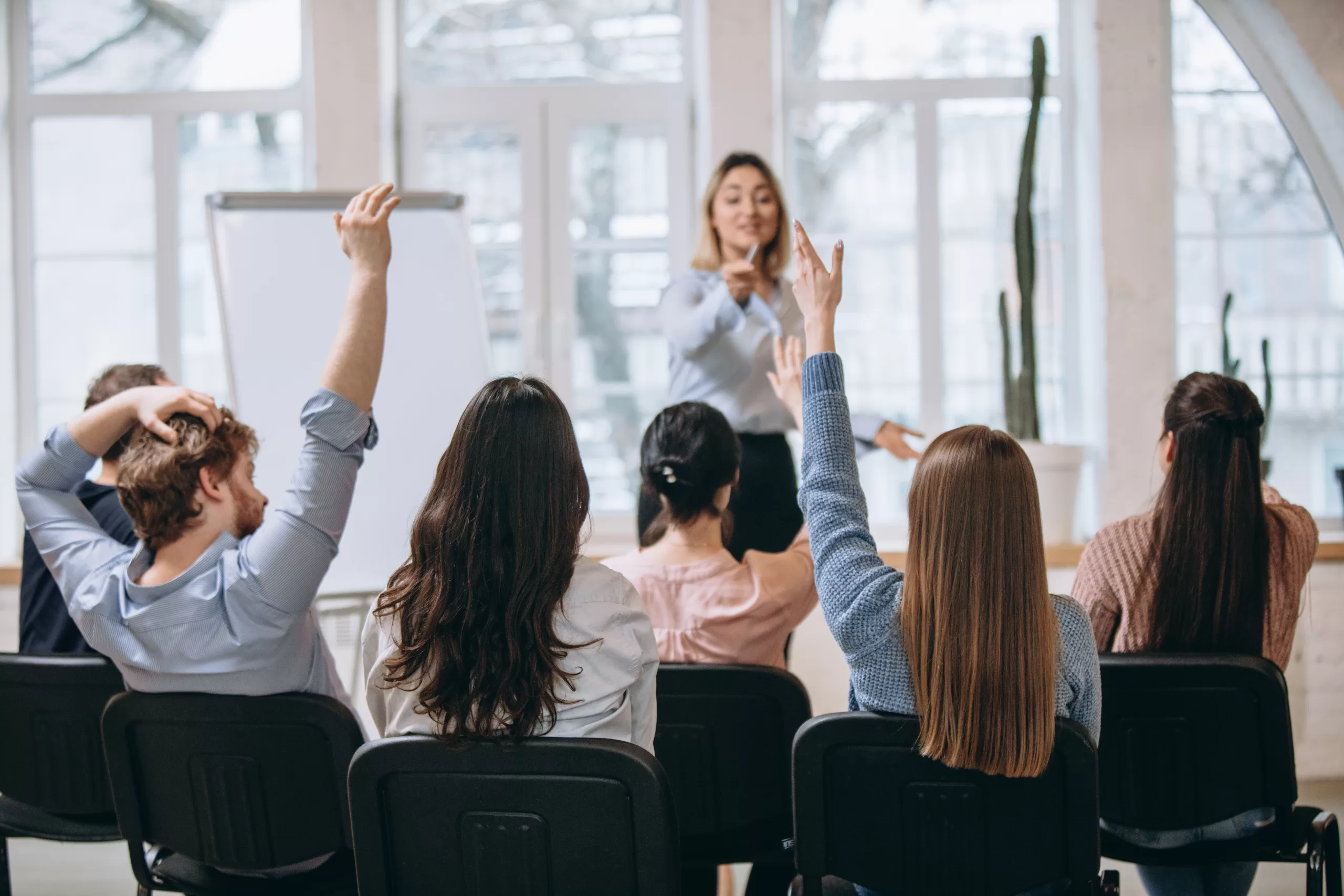 Increase. Female speaker giving presentation in hall at university workshop. Audience or conference hall. Rear view of unrecognized participants. Scientific, business event, training. Education